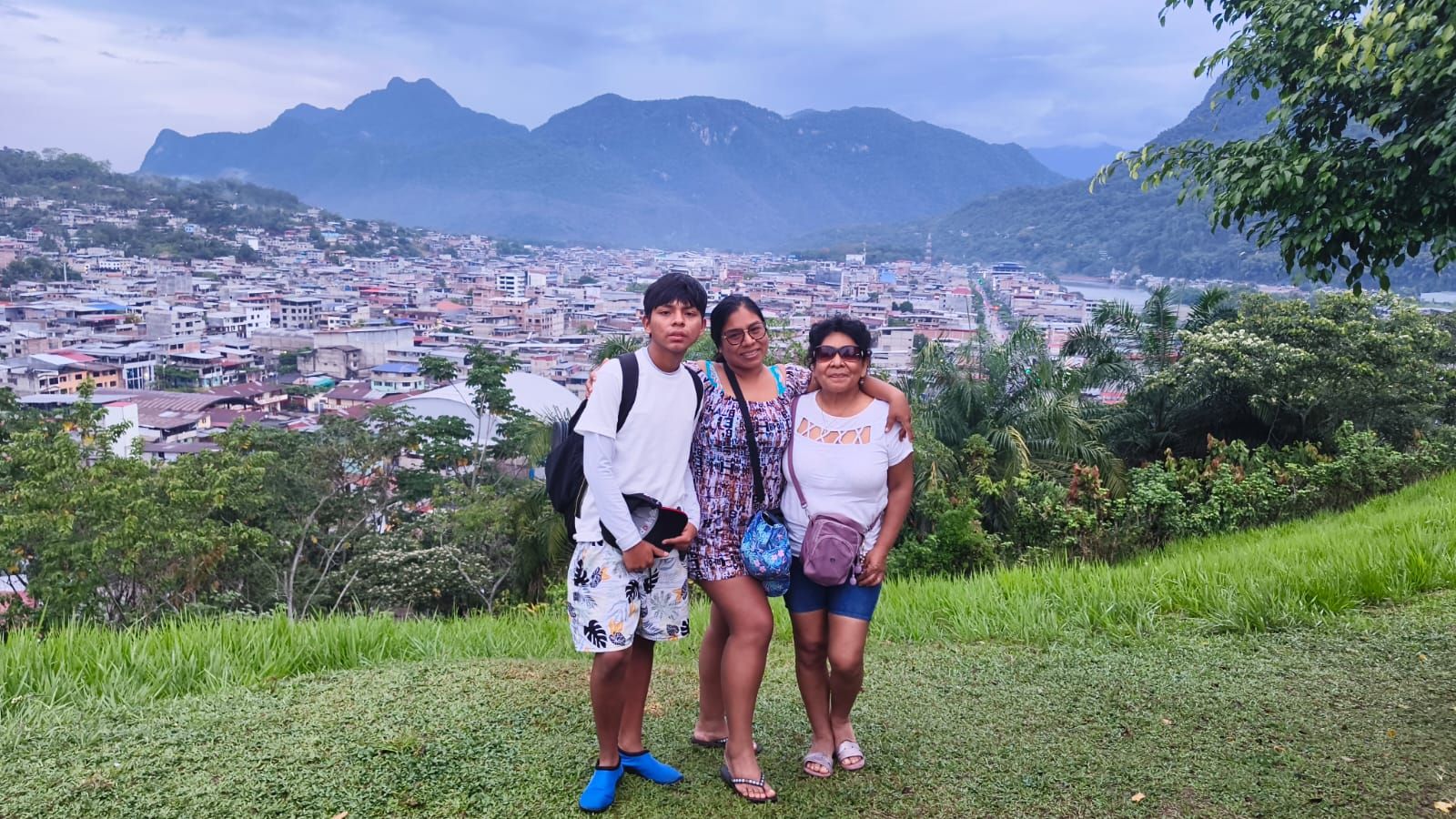 Tres visitantes en una loma con vista a la ciudad de Tingo María y las montañas
